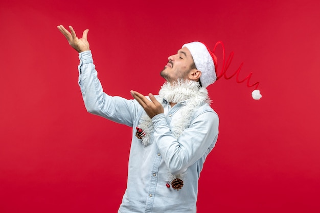 Vue de face du jeune homme avec une expression ravie sur le mur rouge