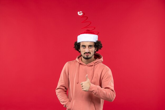 Vue de face du jeune homme avec une expression sérieuse sur le mur rouge