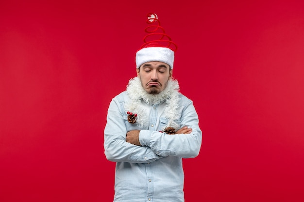 Vue de face du jeune homme avec une expression triste sur le mur rouge