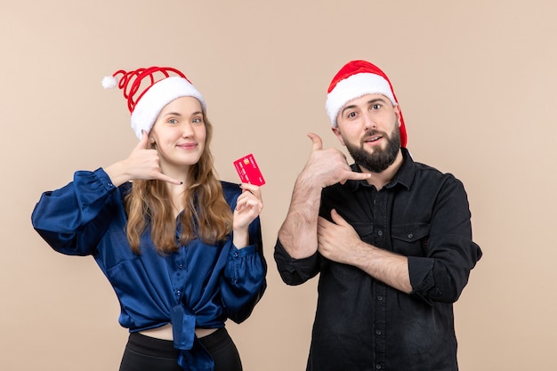 Vue de face du jeune homme avec femme qui tient une carte bancaire sur le mur rose