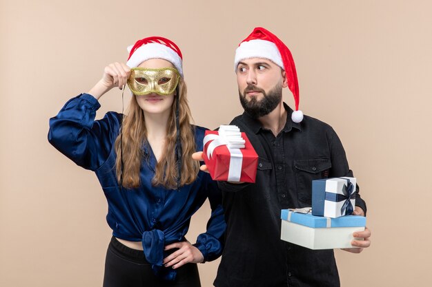 Vue de face du jeune homme avec femme tenant des cadeaux sur le mur rose