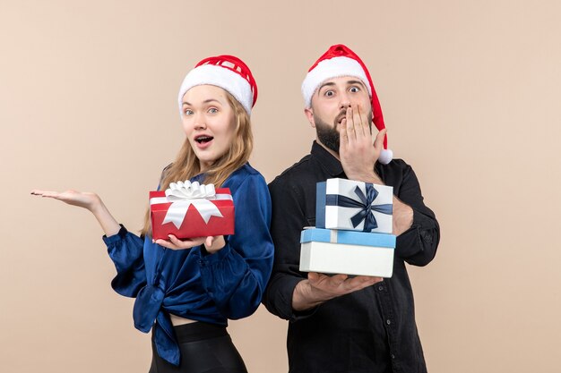 Vue de face du jeune homme avec femme tenant des cadeaux sur le mur rose