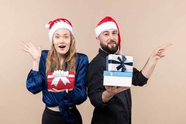 Vue de face du jeune homme avec femme tenant des cadeaux sur le mur rose