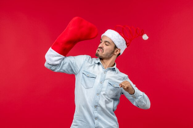 Vue de face du jeune homme avec grosse chaussette sur mur rouge