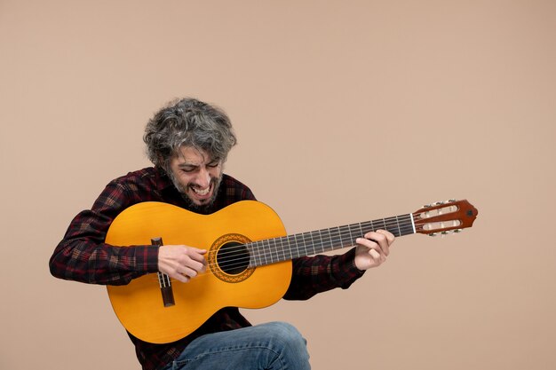 Vue de face du jeune homme avec guitare sur le mur rose