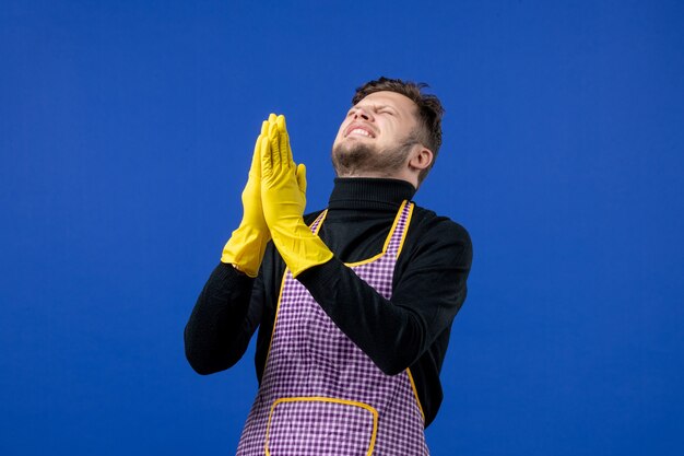 Vue de face du jeune homme joignant les mains et souhaitant sur le mur bleu