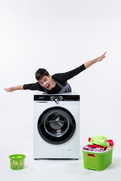 Photo gratuite vue de face du jeune homme avec lave-linge et vêtements sales sur mur blanc