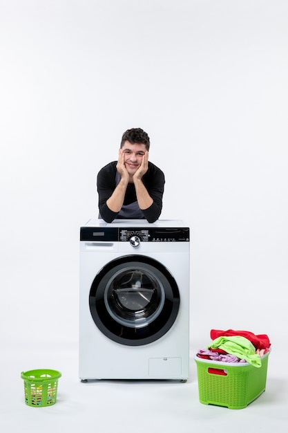 Photo gratuite vue de face du jeune homme avec lave-linge et vêtements sales sur mur blanc