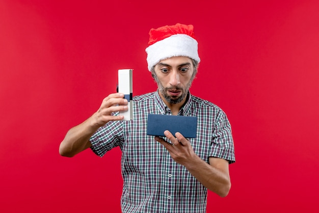Vue de face du jeune homme ouvrant le cadeau de Noël sur le rouge