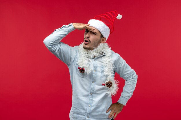 Vue de face du jeune homme regardant à distance sur un mur rouge