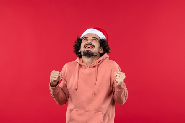 Vue de face du jeune homme se réjouissant joyeusement sur le mur rouge