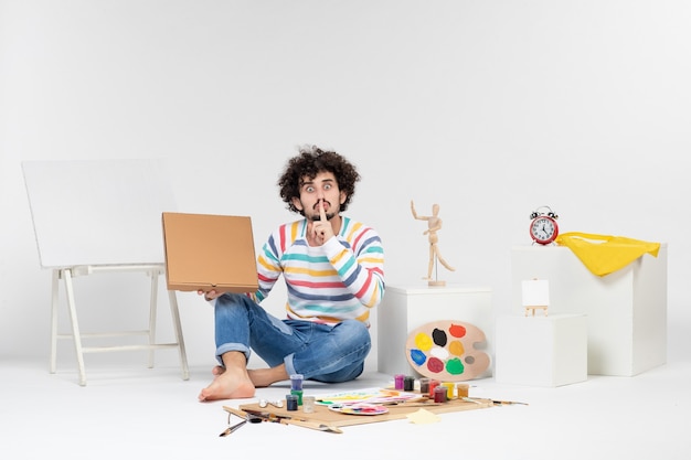 Photo gratuite vue de face du jeune homme tenant une boîte à pizza sur un mur blanc