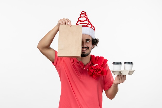 Vue de face du jeune homme tenant un café de livraison sur un mur blanc