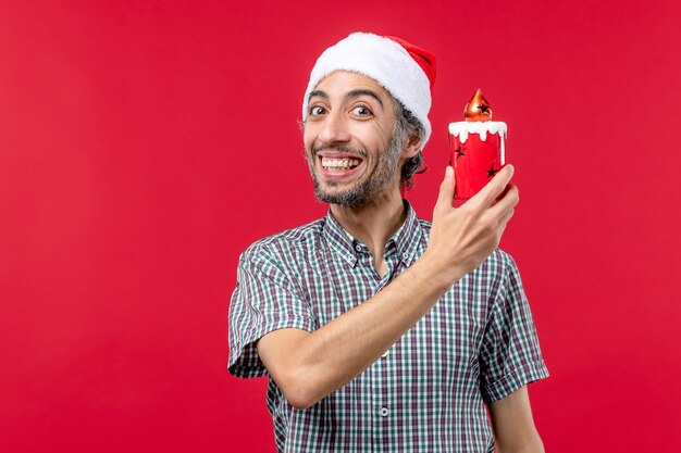 Vue de face du jeune homme tenant un petit jouet sur le rouge