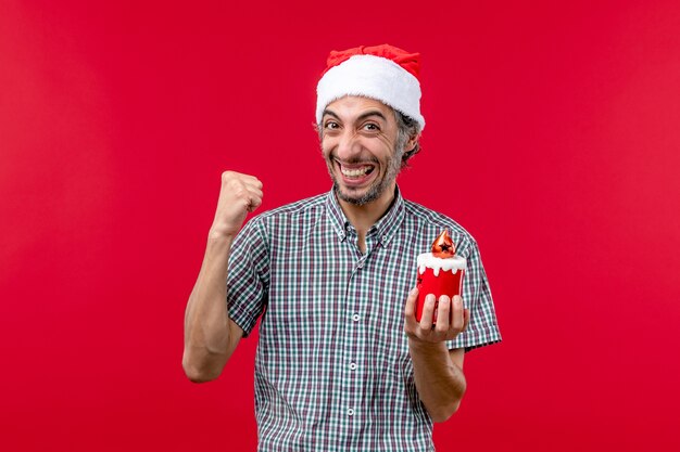 Vue de face du jeune homme tenant un petit jouet sur le rouge