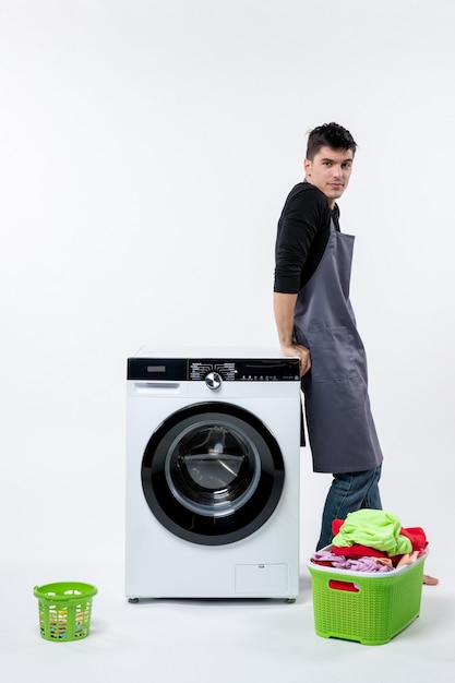 Photo gratuite vue de face du jeune homme avec des vêtements sales et une laveuse sur un mur blanc