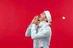 Photo gratuite vue de face du jeune homme avec visage priant sur mur rouge