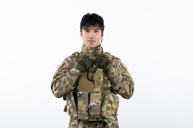 Vue de face du jeune soldat en uniforme militaire sur mur blanc