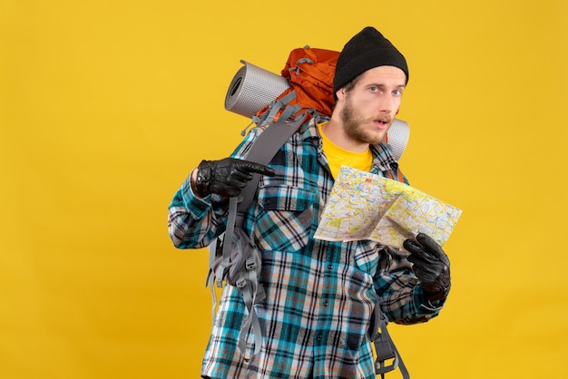 Photo gratuite vue de face du jeune touriste barbu avec des gants en cuir et sac à dos pointant sur la carte