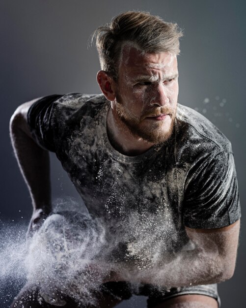 Vue de face du joueur de rugby masculin athlétique tenant le ballon avec de la poussière