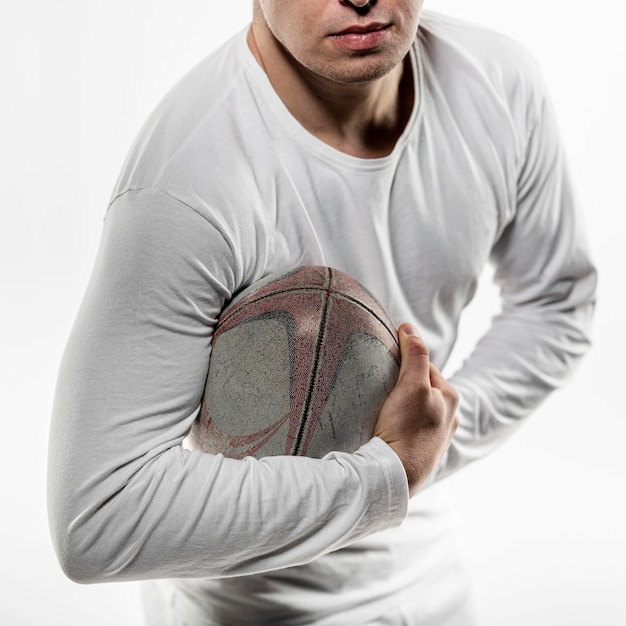 Vue de face du joueur de rugby masculin posant tout en tenant le ballon