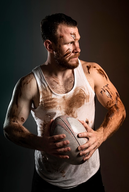 Photo gratuite vue de face du joueur de rugby masculin sale athlétique holding ball