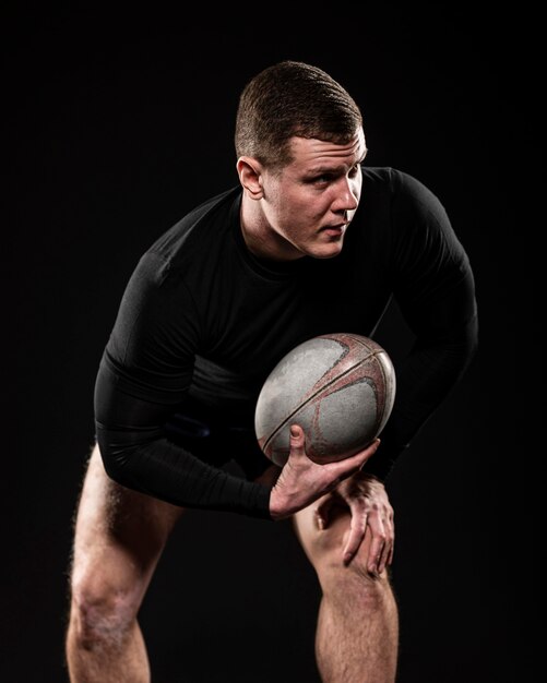 Vue de face du joueur de rugby masculin tenant le ballon avec une main