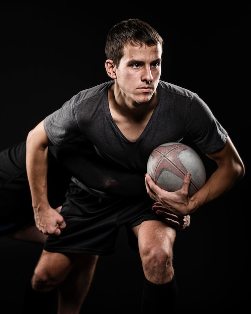 Vue de face du joueur de rugby masculin tenant le ballon avec son bras