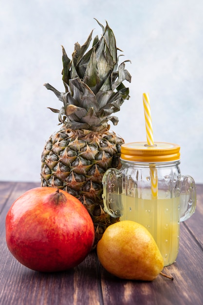 Vue de face du jus d'ananas à l'ananas grenade pêche sur surface en bois et surface blanche