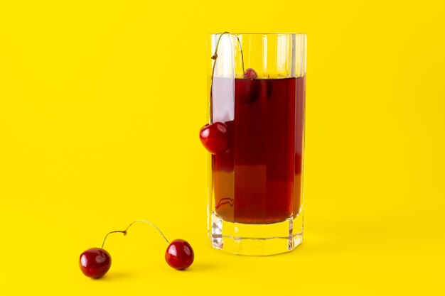 Vue de face du jus de cerise à l'intérieur d'un long verre sur la surface jaune