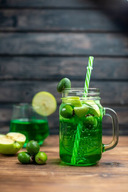 Vue de face du jus de feijoa vert à l'intérieur de la boîte avec des pommes vertes sur un bureau en bois, un bar en bois, une boisson aux fruits de couleur cocktail photo