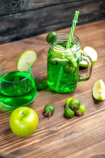 Vue de face du jus de feijoa vert à l'intérieur de la boîte avec des pommes vertes sur un bureau en bois, un bar en bois, une boisson aux fruits de couleur cocktail photo