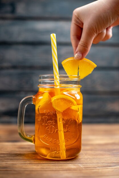 Vue de face du jus d'orange frais à l'intérieur de la boîte avec de la paille sur un cocktail de couleur de fruits noirs