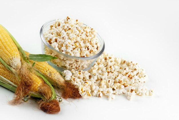 Une vue de face du maïs soufflé frais avec du jaune, des grains crus sur blanc, des graines de collation de repas alimentaire
