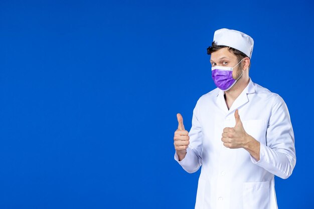 Vue de face du médecin de sexe masculin en costume médical et masque violet sur bleu