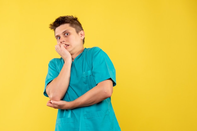 Vue de face du médecin de sexe masculin en costume médical sur mur jaune