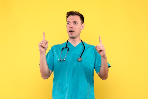 Vue de face du médecin de sexe masculin avec une expression excitée sur le mur jaune