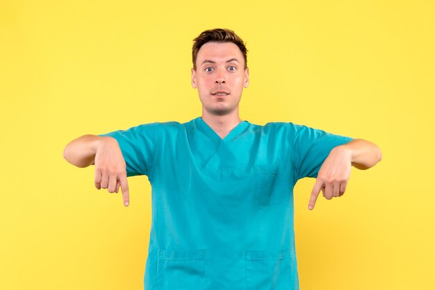 Vue de face du médecin de sexe masculin avec une expression excitée sur le mur jaune