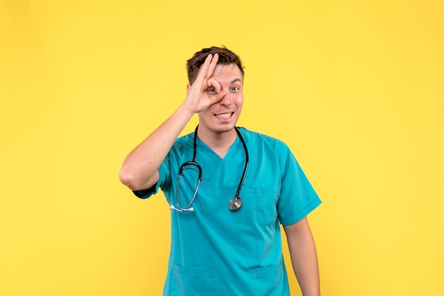 Vue de face du médecin de sexe masculin avec une expression excitée sur le plancher jaune émotion infirmier de l'hôpital