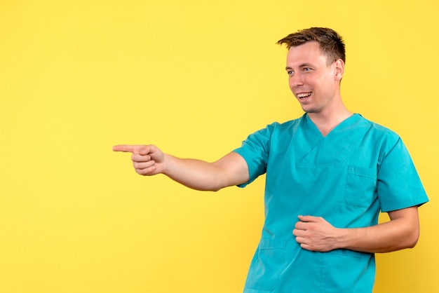 Vue de face du médecin de sexe masculin avec expression de rire sur le mur jaune