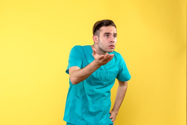 Vue de face du médecin de sexe masculin faisant valoir sur le mur jaune