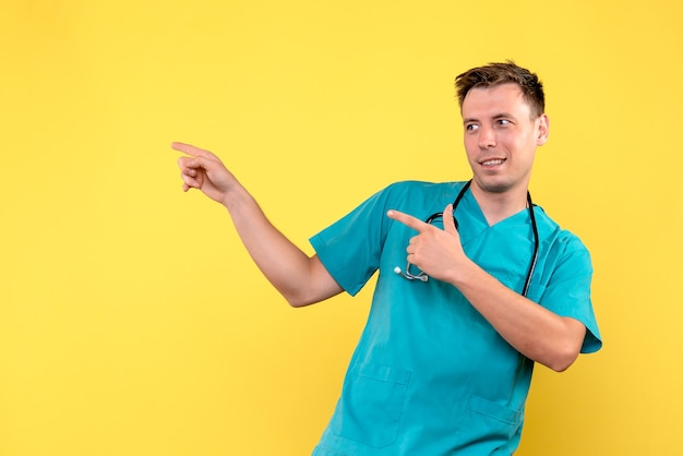 Vue de face du médecin de sexe masculin juste debout sur le mur jaune