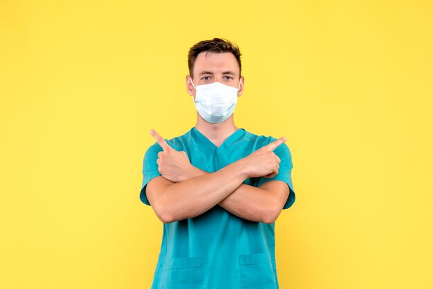 Vue de face du médecin de sexe masculin en masque de protection sur mur jaune