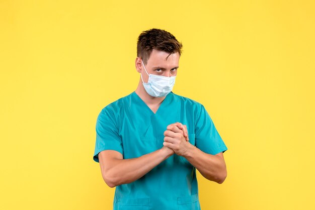 Vue de face du médecin de sexe masculin en masque de protection sur mur jaune