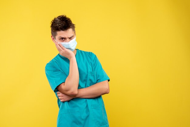 Vue de face du médecin de sexe masculin en masque de protection sur mur jaune