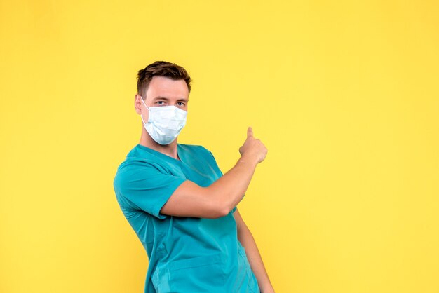 Vue De Face Du Médecin De Sexe Masculin Avec Masque Stérile Sur Mur Jaune