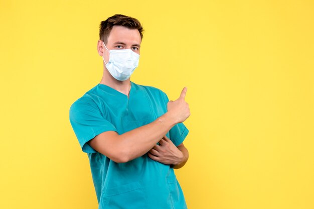 Vue de face du médecin de sexe masculin en masque stérile sur le sol jaune émotion médecin hospital male