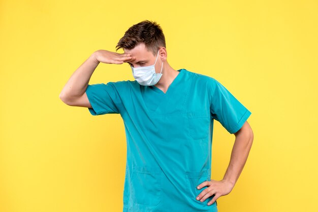 Vue de face du médecin de sexe masculin regardant le plancher sur le mur jaune