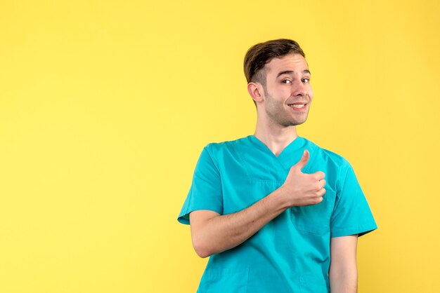 Vue de face du médecin de sexe masculin souriant sur mur jaune