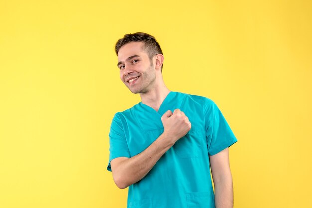 Vue de face du médecin de sexe masculin souriant sur mur jaune